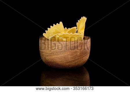 Lot Of Whole Yellow Pasta Farfalle In Bamboo Bowl Isolated On Black Glass