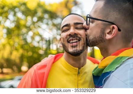 Gay Couple Embracing And Showing Their Love With Rainbow Flag.