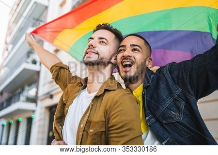 Gay Couple Embracing And Showing Their Love With Rainbow Flag.
