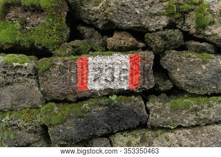 red and white stripes trail mark 736 Piano dei Grilli on volcanic rock in Etna Park, Sicily