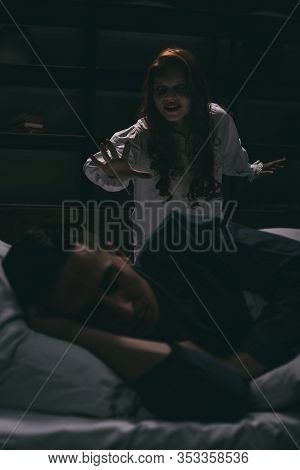 Demoniacal Smiling Woman Standing Over Sleeping Man In Bedroom