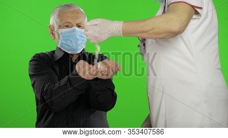 Ederly Grandfather Man In A Medical Protective Mask. Woman Doctor Pours Pills Into His Hands. Virus 