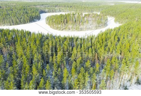 Aerial View Of Frozen Wild Forest Lake At Winter Time. Small Frozen Lake In Green Pine Tree Forest. 