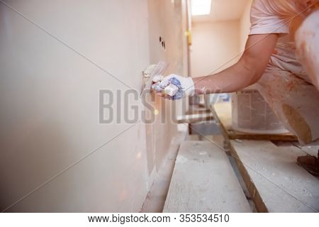 young professional construction worker plastering on gypsum walls inside the new big modern two levels apartment