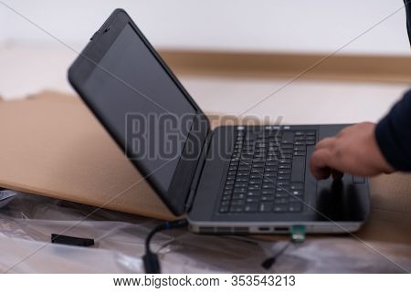 man checking business workflow using laptop computer while lying on floor with cardboard box placed below him during renovation of the apartment