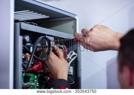 Closeup of electrician engineer working with electric cable wires of modern fuse switch box. Electrical equipment adjusting new voltage wiring