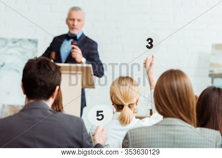 Selective Focus Of Buyer Showing Auction Paddle With Number Three To Auctioneer During Auction