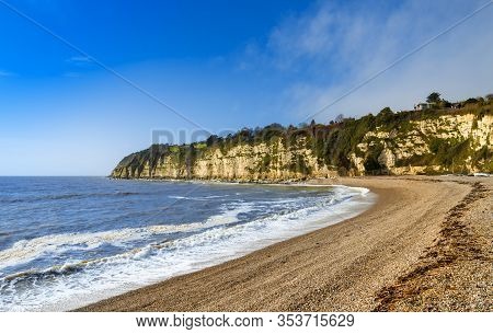 Early Morning Sunlight Illuminates The Pebbles Of The Beach At Beer In Devon
