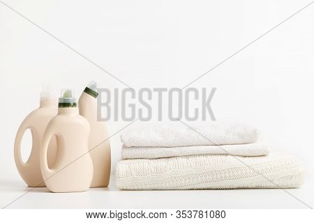 Pile Of Folded Clean Towels With Bio Bottles Packaging For Laundry On White Background. Space For Te
