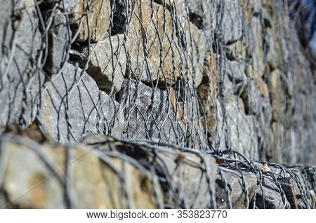 Gabion. Stone Fence In A Metal Mesh. Crushed Stone Packed In Wire Mesh. Granite Texture. Selective F