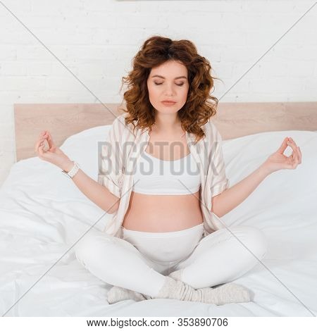 Attractive Pregnant Woman Practicing Yoga On Bed