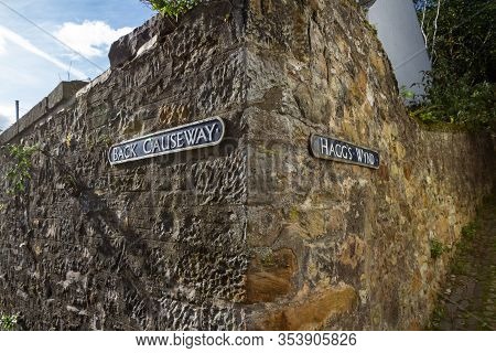 Close Up Of A Corner Wall In Culross Intersecting Two Streets With Aged Signs On A Rock Wall