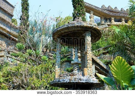 February 26, 2020 In Amatitlan, Guatemala:  Lush Plants Surrounding A Decorative Stone Gazebo And Ru