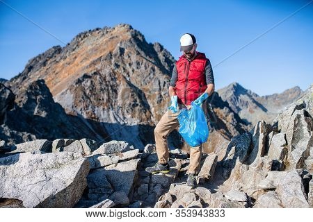 Man Hiker Picking Up Litter In Nature In Mountains, Plogging Concept.