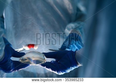 Close-up Of Plastic Surgeon Doing Implantation Procedure With Implants. Practitioner Performing Oper