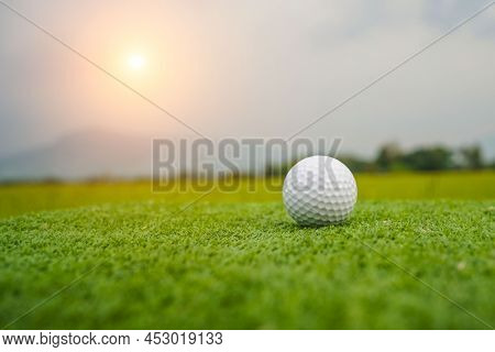 Golf Ball On The Green With Warm Tone And Sunset. Golf Ball On Green Field Golf Course In Morning Ti