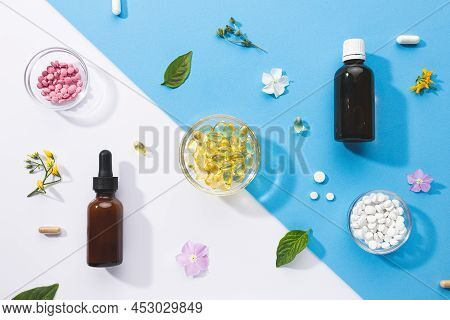 Flat Lay Composition Of Various Vitamin Capsules And Dietary Supplements On Blue And White Backgroun