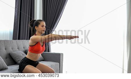 Young Muscular Fitness Woman Doing Half Squats Exercise At Home On Living Room ,sofa Workout