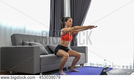 Young Muscular Fitness Woman Doing Half Squats Exercise At Home On Living Room ,sofa Workout
