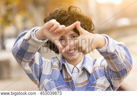 Young Brunette Woman With Curly Hair Making The Framing Sign With Her Hands