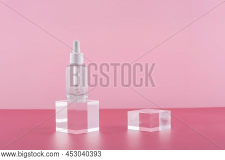 Serum Cosmetic Bottle With Peptides And Retinol On Acrylic Blocks On Pink Background. Cosmetics Tran