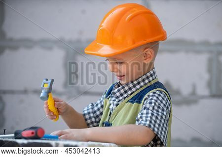 Kid In Hard Hat Holding Hammer. Little Child Helping With Toy Tools On Construciton Site. Kids With 