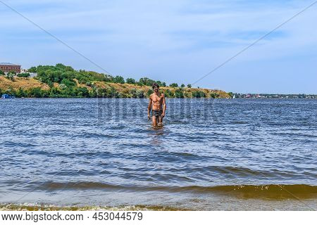A Young Handsome European Man Stands In The Blue Water Of The Inhul River In Mykolaiv, Ukraine. Summ