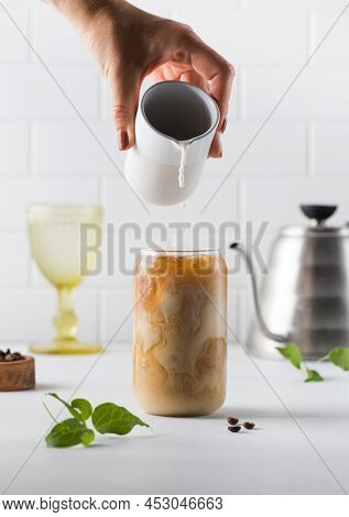 Cream Is Poured Into Cold Black Coffee With Ice Cubes. Coldbrew. Summer Drinks.