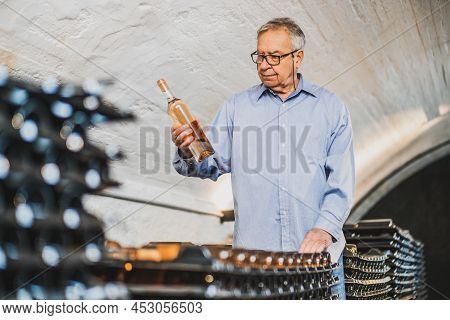 Portrait Of Senior Man Who Owns Winery. He Is Examining Quality In His Wine Cellar. Industry Wine Ma