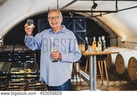 Portrait Of Senior Man Who Owns Winery. He Is Examining Quality In His Wine Cellar. Industry Wine Ma