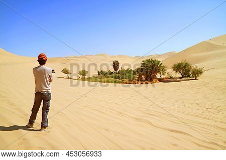 Visitor Looking At The Small Oasis On The Vast Sand Dunes Of Huacachina Desert, Ica Region, Peru