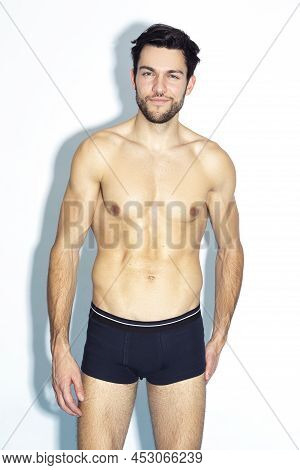 Handsome Caucasian Man Wearing Contrasty Underware Outfit And Posing Over White Background.