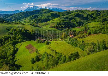 Amazing Summer Scenery With Green Meadows And Agricultural Farmlands On The Slopes, High Snowy Mount