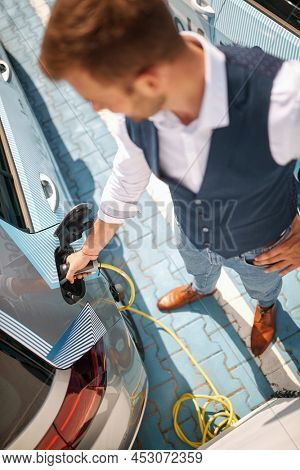 Caucasian busnessman charging his electric car at the charging station