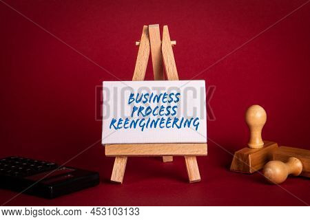 Business Process Reengineering. Miniature Easel With Office Supplies On A Red Background