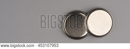 Two Round Flat Batteries On A Gray Background. Lots Of Space For Text