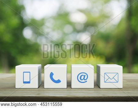 Mobile Phone, Telephone, Email Address And Mail Icon On White Block Cubes On Wooden Table Over Blur 