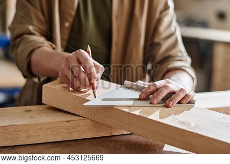Horizontal Shot Of Unrecognizable Woodshop Worker Drawing Marks On Wood Plank Section To Cut