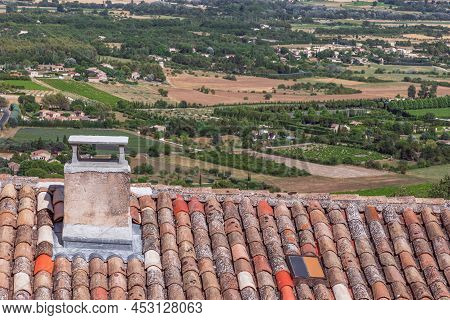 Tiled Roof With Chimney And Window Of Gordes Rock Village And Panoramic View Of Luberon Valley With 