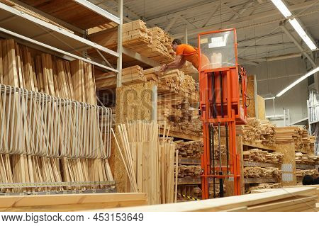 Sale Of Lumber. Large Selection Of Lumber. A Worker Stands On A Lift And Stacks Goods On A Shelf In 