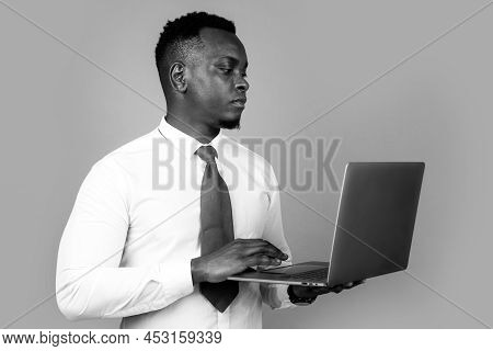 Young Businessman Using Laptop And Taking Notes At Worklace In Modern Office, Free Space