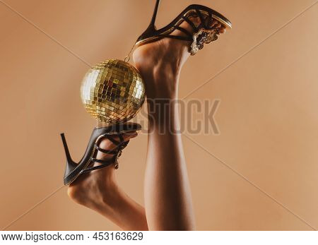Sexy Woman Legs. Disco Party Event. Woman High Heels With Gold Disco Ball. Celebrating Background.