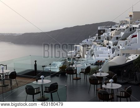Imerovigli, Santorini, Greece - July 1, 2021: Tables On The Restaurant Terrace With A Picturesque Vi