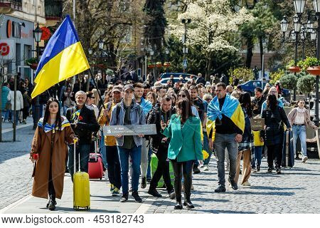 Uzhhorod, Ukraine - April 19, 2022: Ukrainian Refugees With Suitcases Walk In The City Center During