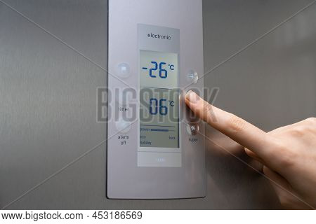 Close-up Of A Woman's Hand Regulates The Temperature Of The Refrigerator Freezer. Stylish Modern Gre
