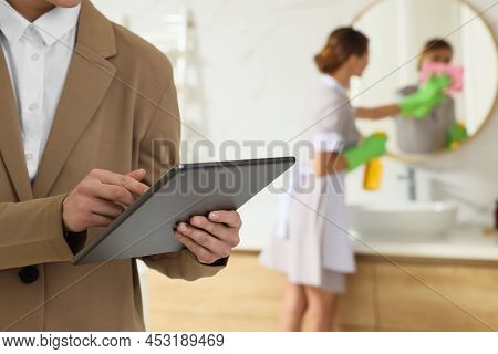 Housekeeping Manager With Tablet Checking Maid's Work In Hotel Bathroom, Closeup