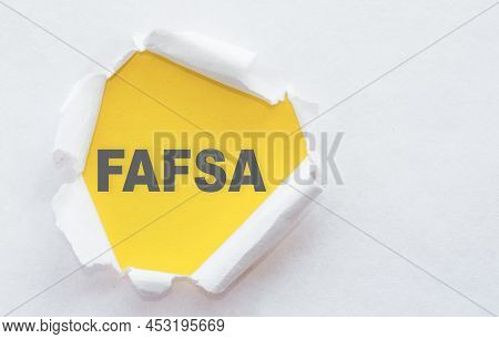 Phrase Fafsa Free Application For Federal Student Aid Appearing On Yellow Surface Under Torn White P