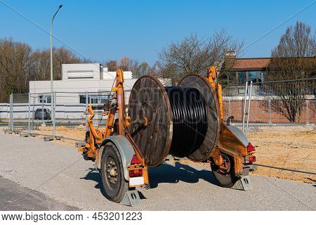 A Wooden Reel With An Electric Cable Is Mounted On A Two-wheeled Trailer. Construction Site. Buildin