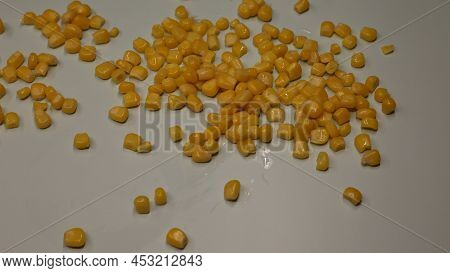Yellow Corn Is Scattered On The Table. A Can Of Canned Corn With Juice Is Open And Stands On A Woode