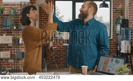 Colleagues Giving Highfive While Brainstorming Ideas To Design Project And Plan Marketing Strategy. 